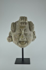 Maya 550 - 950 AD. H 26cm, W 12cm. Stucco head of a man with elderly, wrinkled features above the prominent nose, half-closed eyelids and open mouth, ...