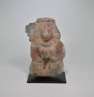 Maya, 550 - 950 AD. H 22cm. Clay figurine with red, blue, yellow and black painting, depicting a man seated with crossed legs, headdress, necklace and...