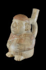 Moche, 100 - 300 AD. H 13.8cm. Reddish clay painted in beige and red. Stirrup vessel in form of a sitting male wearing a headpiece extending to the ba...