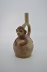 Moche, 300 - 700 AD. H with handle 28cm. Stirrup vessel of red-painted clay, with a lying ape modeled ontop of its body. Separation at the bottom. Gef...