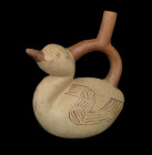 Moche, 300 - 700 AD. H with handle 23.3cm, H of figure 17.8cm. Reddish clay painted in red and beige. Stirrup vessel in form of a duck with long neck....