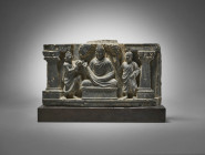 Relief from a stupa base with Buddha. Gandhara, 2nd - 3rd century AD. Height 12,2cm and with base 14,4cm, width 22cm, depth 5,2cm. Grey shist. In the ...