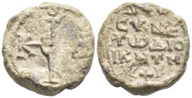 Byzantine Lead Seal, (18mm, 11.3 g) Cruciform monogram. / Legends in four lines.