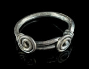 A ROMANO-CELTIC SILVER RING WITH TWO SPIRALS
Circa 1st century AD.
With two spirals and overlapping ends secured with spiral twists. 
Ring size 56 (EU...