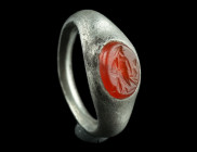 A ROMAN SILVER RING WITH A CARNELIAN INTAGLIO
Circa 2nd century AD.
Ring with flared shoulders and raised oval bezel set with a carnelian intaglio dep...