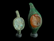 TWO ROMAN BRONZE RING BEZELS WITH INTAGLIOS
Circa 2nd-3rd century AD.
Top parts of two small rings with oval intaglios. The carnelian intaglio depicts...
