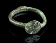 A BYZANTINE BRONZE RING WITH A CROSS
Circa 6th-7th century AD.
Ring with circular bezel decorated with an incised cross and punched ring-and-dot motif...