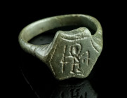 A MEDIEVAL BRONZE RING WITH A STYLISED FIGURE
Circa 14th-15th century AD.
Ring with hexagonal bezel depicting a standing nimbate figure with a spear, ...