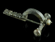 A LATE ROMAN BRONZE CROSSBOW BROOCH
Circa 4th century AD.
With arched bow and onion-shaped terminals ('Zwiebelknöpfe'). The top of the bow and the foo...