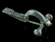 A LATE ROMAN BRONZE CROSSBOW BROOCH
Circa 4th century AD.
With arched bow and onion-shaped terminals ('Zwiebelknöpfe'). The top of the bow and the foo...