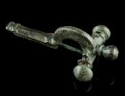 A SMALL LATE ROMAN BRONZE CROSSBOW BROOCH
Circa 4th century AD.
With arched bow and onion-shaped terminals ('Zwiebelknöpfe'). The foot features a carv...