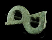 A ROMAN BRONZE S-SHAPED BROOCH
Circa 2nd-3rd century AD.
Plate brooch in the shape of a reversed S, the expanded ends with notched edges. Hinged; pin ...
