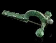 A LATE ROMAN BRONZE CROSSBOW BROOCH
Circa 4th century AD.
With arched bow and facetted onion-shaped terminals ('Zwiebelknöpfe'). Bow and foot decorate...