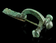 A LATE ROMAN BRONZE CROSSBOW BROOCH
Circa 4th century AD.
With arched bow and onion-shaped terminals ('Zwiebelknöpfe'). The top of the bow is decorate...