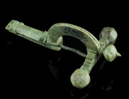 A LATE ROMAN BRONZE CROSSBOW BROOCH
Circa 4th century AD.
With arched bow and facetted onion-shaped terminals ('Zwiebelknöpfe'). The top of the bow is...