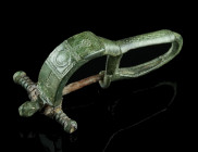 A BYZANTINE BRONZE BROOCH WITH BENT FOOT
Circa 6th-7th century AD.
Cast bow brooch with folded foot (umgeschlagenem Fuß). Incised and punched decorati...