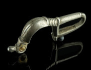 A BYZANTINE SILVER BROOCH WITH BENT FOOT
Circa 6th-7th century AD.
Cast bow brooch with folded foot ('umgeschlagenem Fuß'); incised and punched decora...