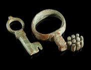 TWO ROMAN BRONZE KEYS
Circa 1st-4th century AD.
A key ring with short projecting shank and offset key bit, and a small Late Roman rotary key with holl...