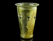 A LATE ANTIQUE YELLOW-GREEN GLASS BEAKER
Circa 4th-5th century AD.
Conical glass beaker with flat base and flaring mouth. Halfway on the body a patter...