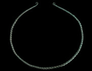 A LARGE EUROPEAN LATE BRONZE AGE TWISTED TORQUE
Circa 1000-800 BC.
Twisted hoop of solid bronze, the plain tapering ends with flattened coiled termina...