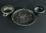 A GROUP OF THREE WESTERN GREEK BLACK-GLAZED VESSELS
Circa 4th-early 3rd century BC.
A black-glazed plate, a cup with one looped handle, and a further ...