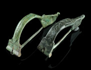 TWO ROMAN BRONZE WOLF HEAD BROOCHES
Circa late 1st-2nd century AD.
Two bow brooches decorated with a stylised wolf's head and a punched design. Both h...