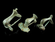 A GROUP OF THREE ROMAN BRONZE KNEE BROOCHES
Circa 2nd-3rd century AD.
Two brooches with faceted bow, transverse catch plate and hinged pin. And a broo...