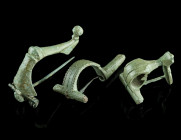 A GROUP OF THREE ROMAN BRONZE BROOCHES
Circa 2nd-3rd century AD.
A strongly profiled brooch with spring and pin, an ornate knee brooch with hinged pin...