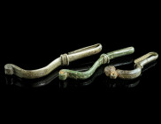 A GROUP OF THREE BRONZE BROOCHES WITH BENT FOOT
Circa 4th-5th century AD.
Bow brooches with folded foot (umgeschlagenem Fuß); all with punched decorat...
