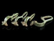 A GROUP OF FOUR BYZANTINE BRONZE BROOCHES WITH BENT FOOT
Circa 6th-7th century AD.
Cast bow brooches with folded foot (umgeschlagenem Fuß), mostly wit...