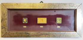 INGHILTERRA. Cornice contenente riproduzioni in metallo dorato di tre francobolli inglesi: penny black 1840, 5 pounds 1882 e 10 shillings 1867. 150x35...