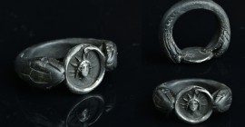 Serpent formed ring with an silver detailed Hellios.
11,37 g - 25,52 mm