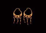 Parthian Gold Earrings with Garnet Drops
1st century BC. A matched pair of gold earrings, each a crescent plaque with ends extended to form a hook-an...