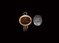 Roman Gold Pendant with Gemstone
1st-2nd century AD. A high quality garnet with engraved intaglio of Victory in plumed helmet, wings folded to the re...