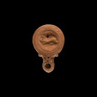 Roman Oil Lamp with Dolphin
2nd century AD. A ceramic oil lamp with rounded long nozzle, volute scroll to each side, deep discus with concentric circ...