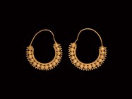 Large Byzantine Gold Loop Earrings
4th-7th century AD. A matched pair of gold earrings, each a wire hoop and band of hollow spheres with filigree cor...