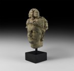 Gandharan Head of Buddha
2nd-4th century AD. A carved schist head of Buddha with youthful features, moustache, headdress with plume; mounted on a cus...