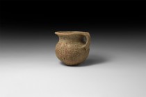 Bronze Age Decorated Single-Handled Cup
Mid 2nd millennium BC. A ceramic cup with bulbous body, narrow shoulder, everted rim, strap handle; bands of ...
