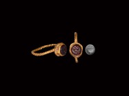 Roman Gold Ring with Gemstone
1st century AD. A gold ring with twisted hoop and drum bezel, inset amethyst intaglio engraved with an image of a winec...
