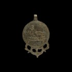 Roman Pendant with Erotic Scene
1st-2nd century AD. A discoid bronze pendant with integral loop, lobes with pelta-shaped openwork detailing, central ...