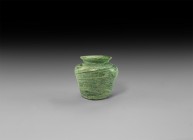 Roman Green Glass Vessel
2nd-3rd century AD. A low jar with broad everted rim and dimple base in green and white glass, swirl pattern. 125 grams, 87m...