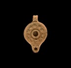 Roman Oil Lamp with Grapevine
2nd-3rd century AD. A ceramic oil lamp with round nozzle, lug handle to the rear, the discus with high-relief band of g...