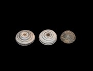 Byzantine Spindle Whorl Collection
6th-10th century AD. A group of three spindle whorls comprising: two in blue glass with white trails; one black st...