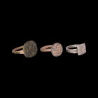Western Asiatic Ring Collection
1st millennium AD. A mixed group of three rings comprising: one silver ring with D-section shank, square bezel with h...