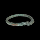 Western Asiatic Bracelet with Animals
1st millennium BC. A bronze penannular bracelet with opposed beast-head finials, pointillé and hatched detailin...
