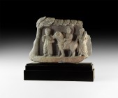 Gandharan Figural Frieze Section
3rd-5th century AD. A carved schist frieze panel depicting a figural group beneath the leafy canopy of a tree; centr...