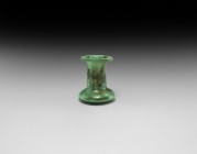 Islamic Green Glass Vessel
13th-14th century AD. A pale green glass vessel with flared base and dimpled underside, tubular body with flared rim; some...