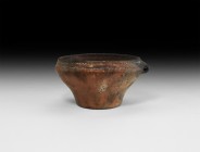 Bronze Age Cord-Decorated Vessel
2nd millennium BC. A terracotta cup with flared body and chamfered shoulder, lateral loop handle, parallel bands of ...