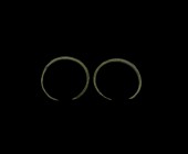 Bronze Age Arm Ring Pair
2nd millennium BC. A pair of bronze round-section penannular arm rings with tapering pointed finials. 125 grams total, 11-11...