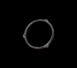 Iron Age Celtic Proto-Money with Faces
1st-2nd century AD. A bronze annular lentoid-section bangle or proto-money with three radiating knops to the o...